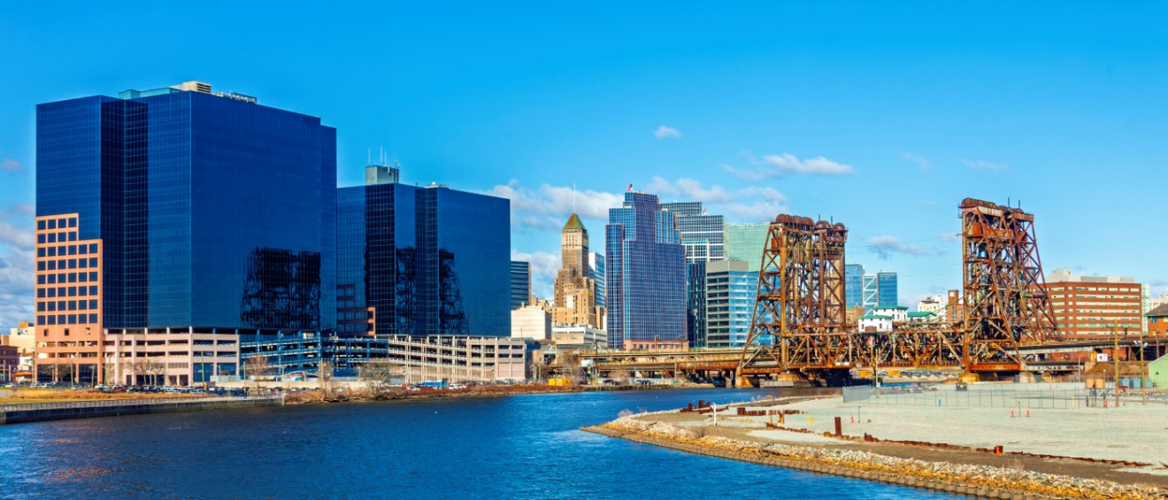 Newark, NJ skyline along the Passaic River with historic rail lift bridges, part of the Newark public transit network connecting the city.